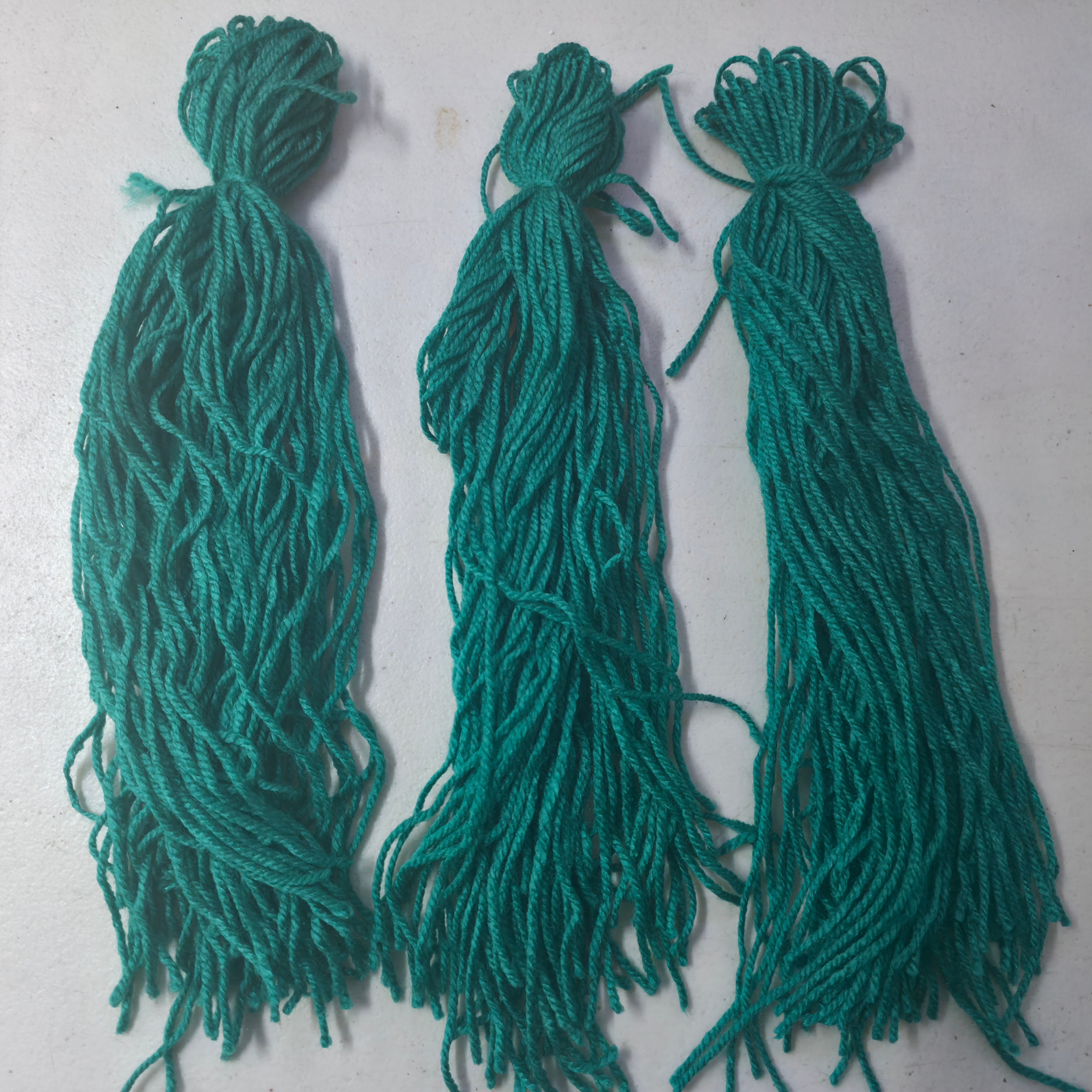Three green spawning mops for fish breeding on a light gray background