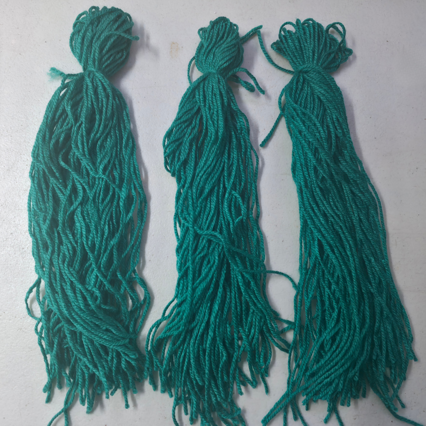 Three green spawning mops for fish breeding on a light gray background